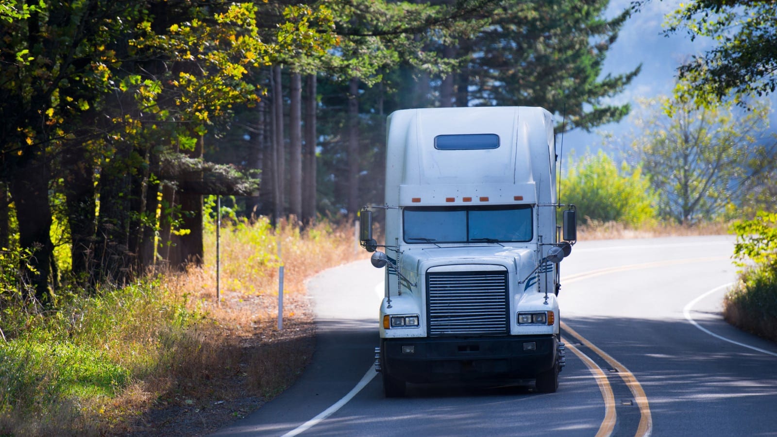 White Semi-truck Driving On A Rural Road Stock Photo