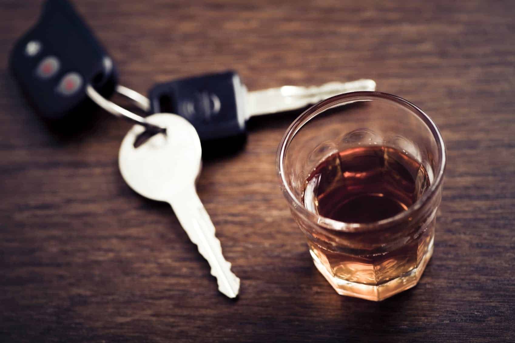 Car Keys Laying Next To A Glass Of Alcohol Stock Photo