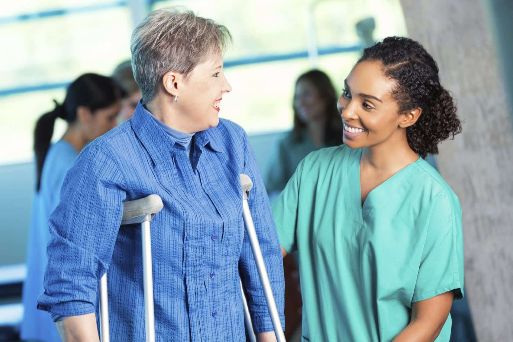Young Nurse Helping Injured Woman On Crutches Stock Photo