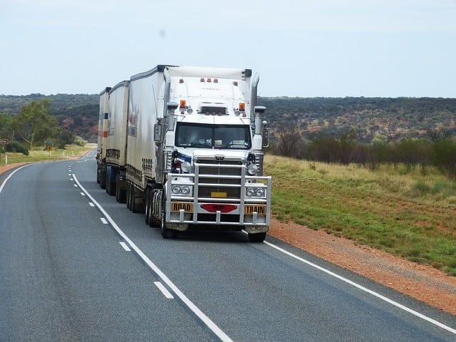 White 18-wheeler Truck Driving On A Rural Highway Stock Photo
