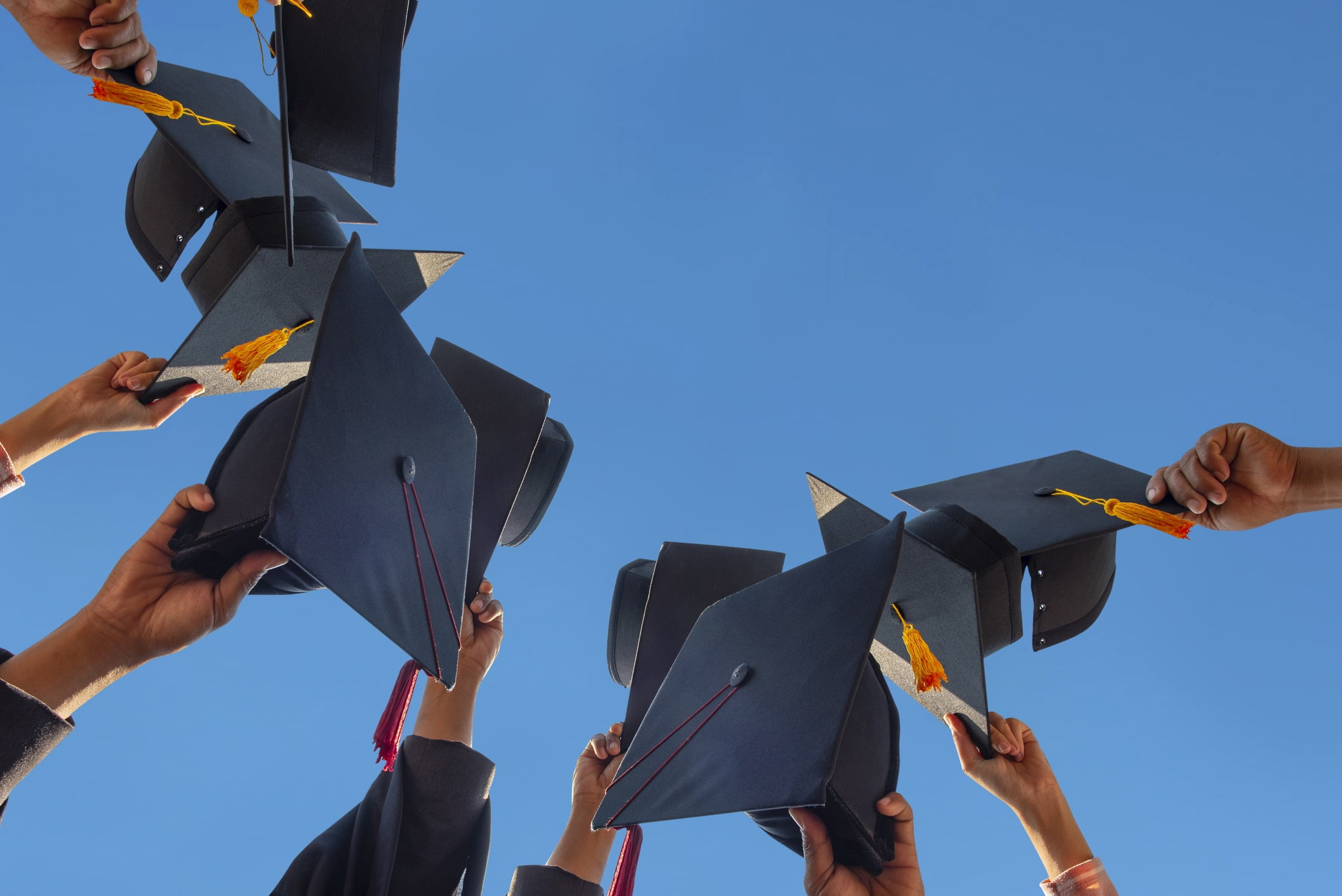 A group of graduates holding their caps in the air.