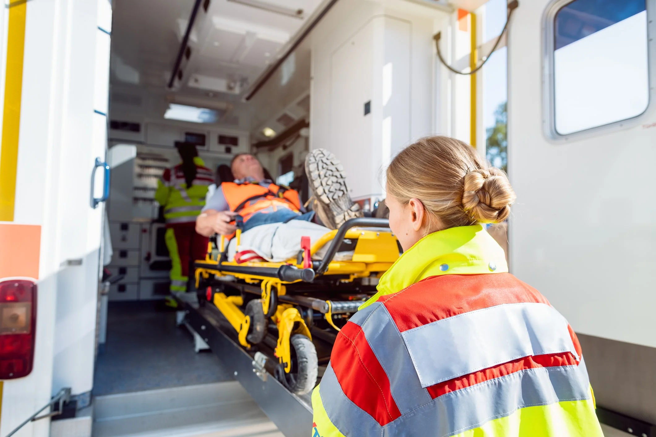 A man being put in an ambulance on a stretcher after suffering injuries from a car accident.