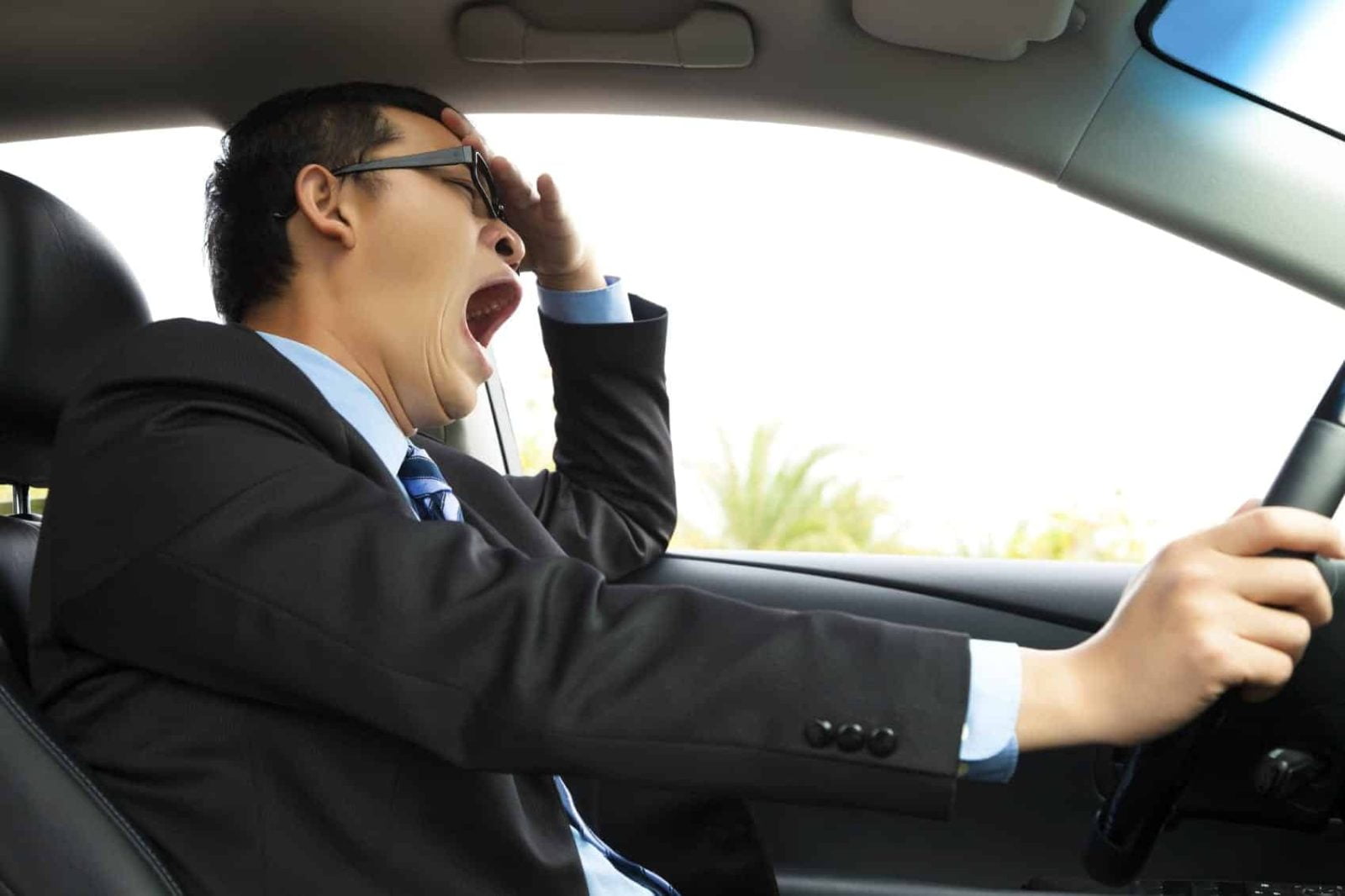 Man Yawning While Driving His Vehicle Stock Photo