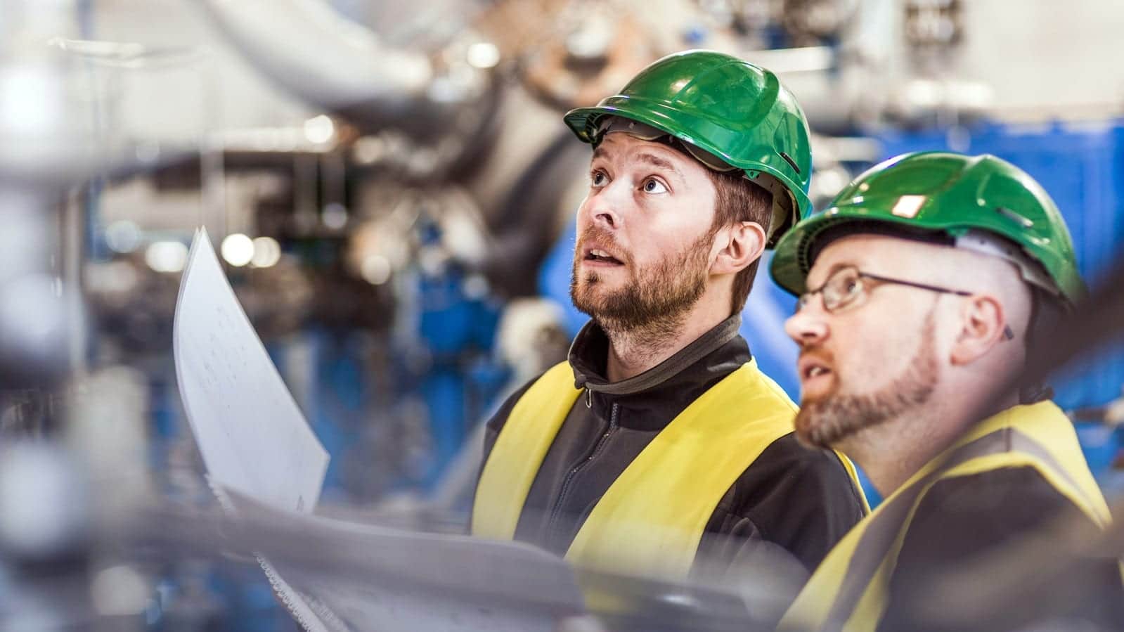 Two Factory Workers In Green Hard Hats Stock Photo
